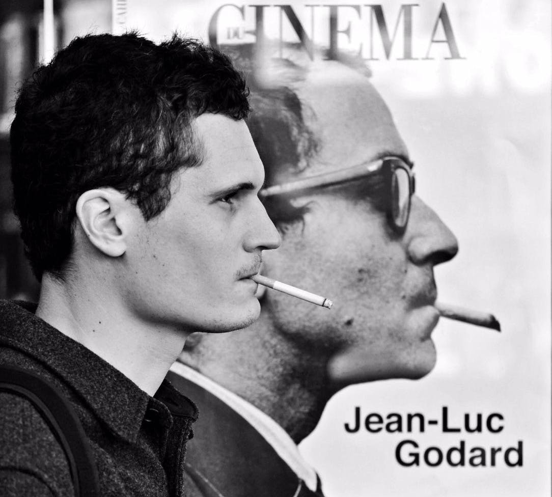 This is a picture of me, smoking a cigarette, in front of a newspaper stand ad for the magazine “Les Cahiers du Cinéma”, featuring a portrait of Jean-Luc Godard—smoking as well. The picture is in black and white, and was taken by a street photographer I didn’t know.